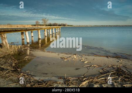 Sandy beach and wooden jetty, evening clouds on a blue sky Stock Photo