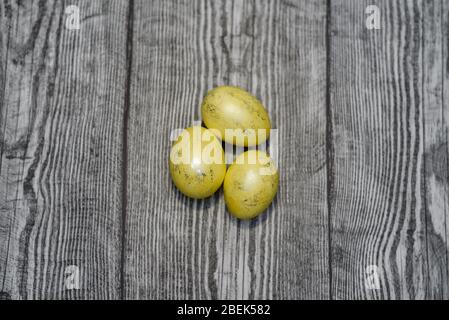 Three chicken yellow eggs laying on the wooden background. Easter colored eggs. Stock Photo