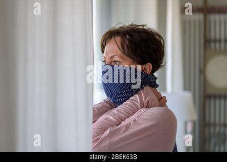 Woman wearing a blue bandanna as a face guard to protect herself against infection by the coronavirus during the Covid-19 pandemic in close up Stock Photo