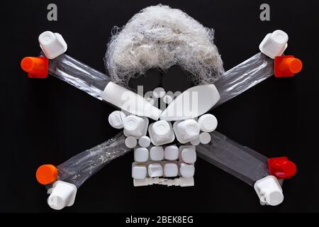 Concept of environmental pollution with plastic waste. Top view of a jolly roger or skull and crossbones symbol made with different plastic objects. Stock Photo