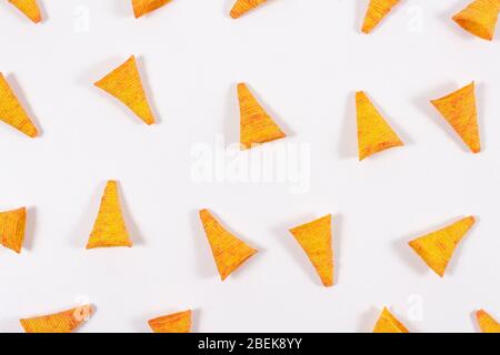 Triangular, corn tortilla chips nachos with unusual shape on bright white background. Open composition. Snack food background. Top view. Mexican food. Stock Photo