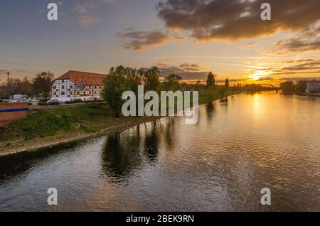 Gorzow Wielkopolski, ger.: Landsberg an der Warthe, Lubusz province, Poland. The Warta riverbank with Granary museum building at the sunset. Stock Photo