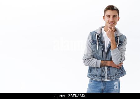 Thoughtful good-looking blond guy consider taking deal, listening to good offer, smiling pleased and pondering decision, touch chin and smirk Stock Photo