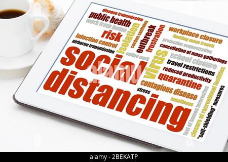 Social distancing concept - a set of  infection control actions to stop or slow down the spread of a contagious disease. Word cloud on digital tablet Stock Photo