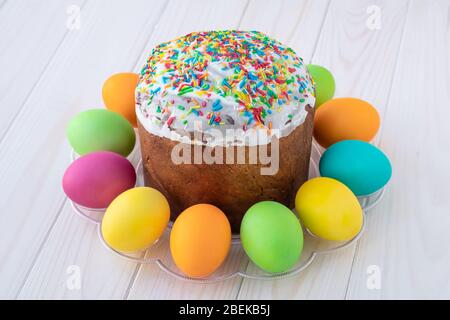 Easter cake and painted multicolored eggs on white wooden boards. Paschal greeting postcard. Light background, planks texture Stock Photo