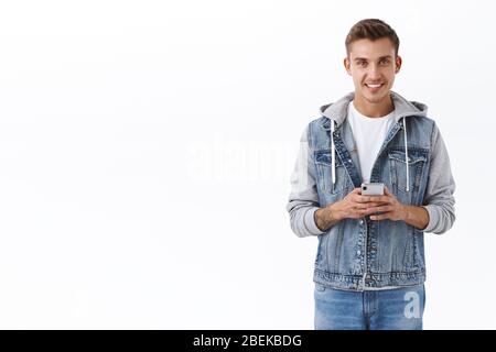 Technology, online shopping and internet communication concept. Portrait of handsome blond man smiling, using mobile phone, texting friend with cell Stock Photo