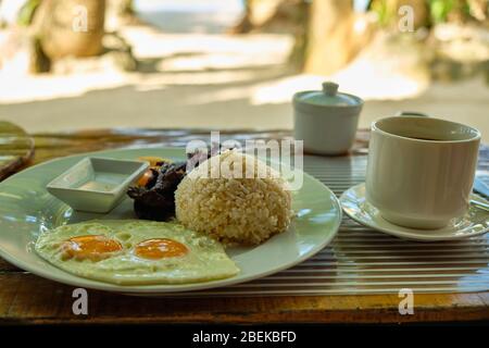 Breakfast on Boracay island of the Philippines with views of the white sandy beach and sea. An omelet and a Cup of coffee in a white dish Stock Photo