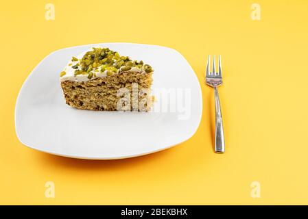 piece of carrot pistachio cake on plate against orange background Stock Photo