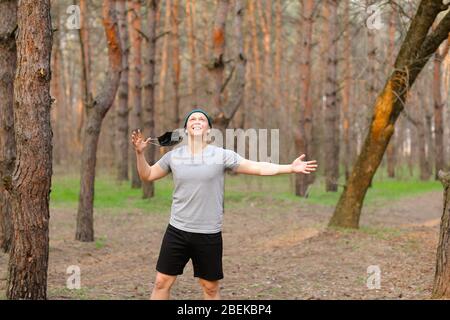 Young man removing mask from face in park. Stock Photo