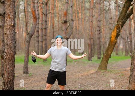Young european man removing mask from face in park. Stock Photo