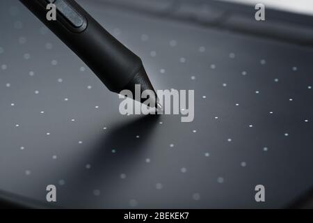 Pen and graphic tablet close-up on a gray textural background. Gadget for working as a designer, artist and photographer. Stock Photo