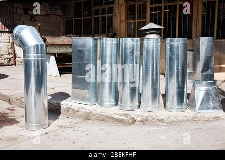 Demounted aluminum chimney pipe hood parts for ventilation on the street in front of a traditional store Stock Photo
