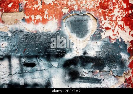 Peeled paint textured wall plaster surface with red and black paint. Grunge cracked wall texture background. Stock Photo