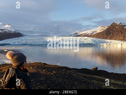 Person beside Fjallsarlon iceberg lagoon, beneath Fjallsjokull glacier. Vatnajokull National Park, Sudhurland, Iceland Stock Photo