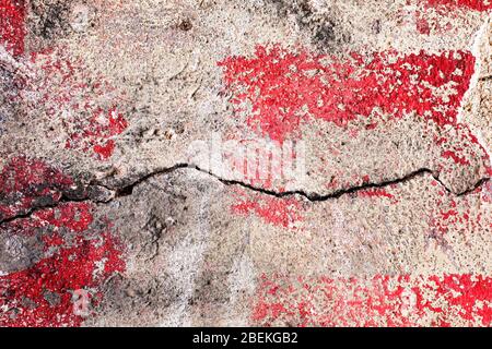Peeled paint textured wall plaster surface with red and black paint. Grunge cracked wall texture background. Stock Photo