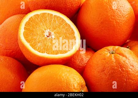 Heap of fresh oranges with one half slice. Close up view. Stock Photo