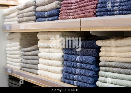 Folded multicolored towels on shelves. Neatly folded clothes. Rack of clothes with warm. Cotton towels neatly folded Stock Photo