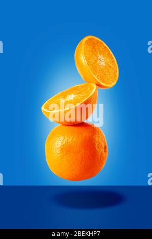 Flying or falling stacked oranges in air on blue background Stock Photo