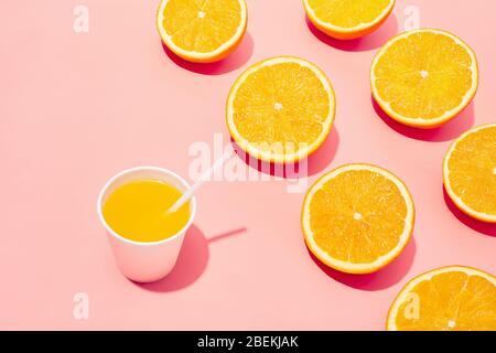Orange juice in a plastic cup with straw and orange slices on pink background. Flat lay minimal concept. Stock Photo