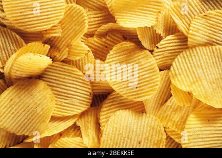 Heap of corrugated potato chips background. Close up macro view Stock Photo
