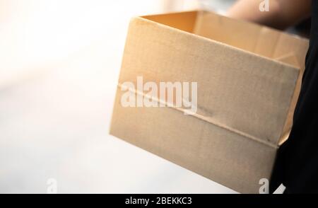 Delivery man hand carrying cardboard box packaging for logistic shipping. Stock Photo