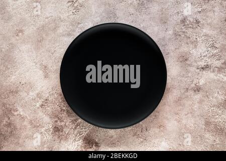 Empty black plate on textured background with copy space. Top view. Stock Photo