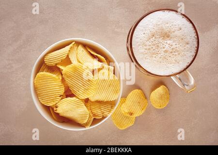 Potato chips and glass of beer on rustic wooden background. Top view Stock Photo