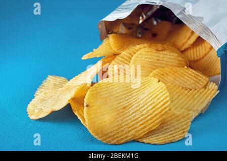 Potato chips in a bag or package spill out on the table. Macro close up view. Stock Photo