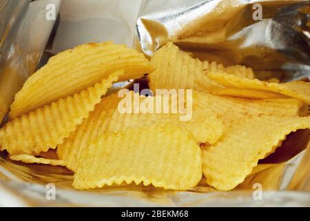 Potato chips in a snack aluminium foil bag or silver package. Macro close up view. Stock Photo