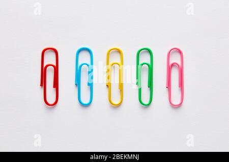 Variety of colorful paper clips in a row on white background. Stock Photo