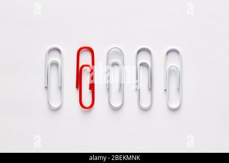 Red paper clip stands out from the crowd. Concept of difference, extraordinary or diversity. Stock Photo