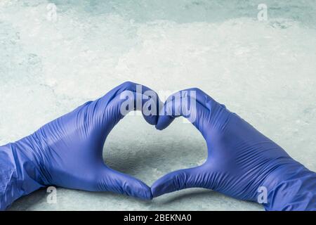 hands in blue latex disposable surgical gloves making heart shape with fingers Stock Photo