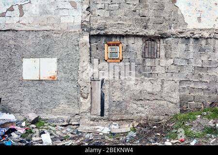 Concrete brick wall and small windows of an abandoned old building exterior. Stock Photo