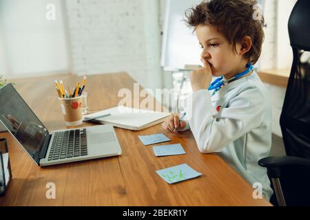 Caucasian teenboy as a doctor consulting for patient, giving recommendation, treating. Little doctor during prescriptioning drugs for patient. Concept of childhood, human emotions, health, medicine. Stock Photo