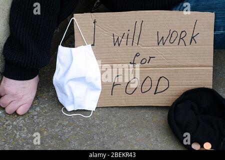 Unemployment concept and unemployed coronavirus sitting on the ground next to it a cardboard plate with the inscription i will work for food, a Stock Photo