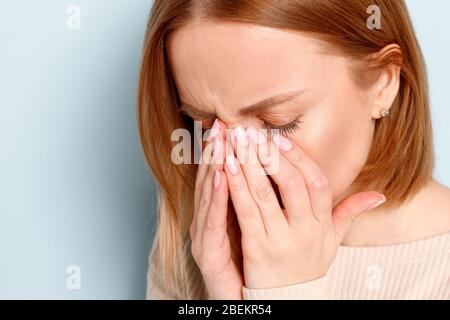 Close uo portrait of young woman has problem with contact lenses, rubbing her swollen eyes due to pollen, dust allergy. Dry eye syndrome, watery, itch Stock Photo