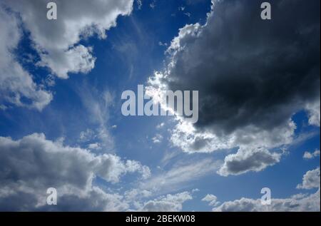 sunshine behind dark clouds on blue sky Stock Photo