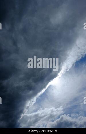 sunshine behind dark clouds on blue sky Stock Photo