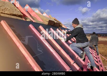 Insulation and waterproofing of the roof surface, the worker nails the film to the boards.2020 Stock Photo