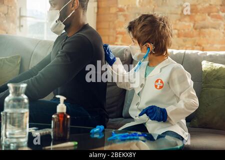Caucasian teenboy as a doctor consulting for patient, giving recommendation, treating. Little doctor during cheking the lungs of his patient. Concept of childhood, human emotions, health, medicine. Stock Photo