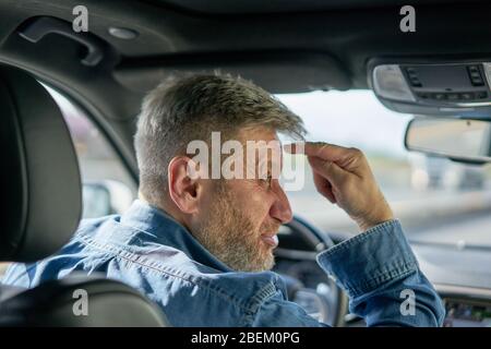 Profile of a very angry and visibly annoyed car driver showing his rage by making an unfriendly gesture Stock Photo