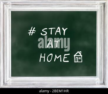 STAY AT HOME written on green chalkboard with drawing of house. Corona virus, covid-19 quarantine concept. Stock Photo