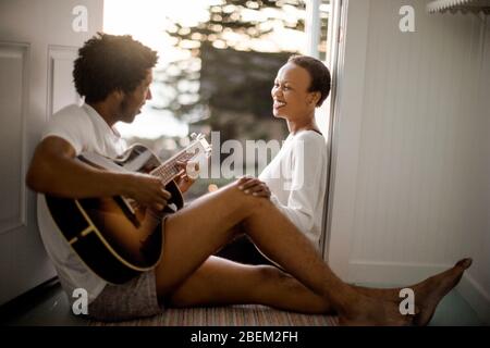 Young man playing guitar for his smiling girlfriend Stock Photo