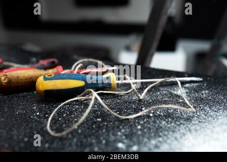 A set of tools for self-installation of the lamp lies on a black table, sprinkled with white dust. Husband for an hour. Household chores Stock Photo