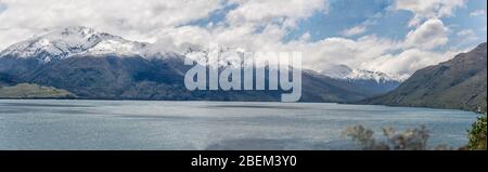 landscape of Wanaka Alpine lake northern part with spring snow on peaks, shot in bright light from west coast from The Neck, Otago, South Island, New Stock Photo