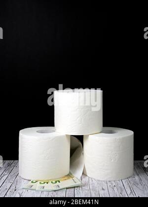 Three rolls of white toilet paper stacked atop each other and three five euro notes Stock Photo