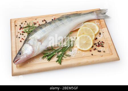 Fresh uncooked pike perch with lemon, rosemary and spice on wooden board isolated on white background with clipping path Stock Photo