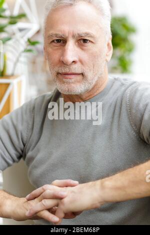 Picture of a mature senior grey-haired bearded businessman sit in cafe. Stock Photo