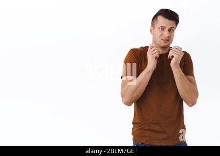 Portrait of scared and insecure handsome young stylish man, hold hands pressed to chest avoid something disgusting or scary, look frightened and Stock Photo