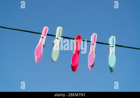 Colourful plastic clothes pegs hanging on a washing line Stock Photo